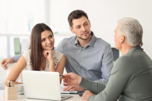Young couple discussing pension plan with consultant in office